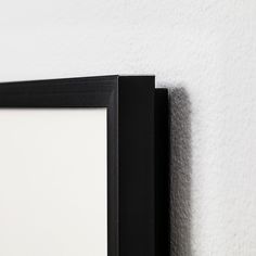 a black frame hanging on the wall next to a white and black framed object with one corner missing