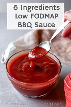 a spoon full of ketchup is being held over a bowl filled with sauce