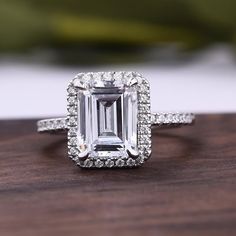 an emerald cut diamond surrounded by diamonds on a wooden surface