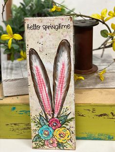 a wooden sign that says hello springtime with two bunny ears and flowers on it