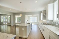 a large kitchen with white cabinets and marble counter tops, along with an island in the middle