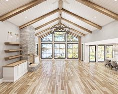 a large open living room with wood flooring and vaulted ceiling, windows overlooking the lake