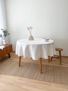 a white table with two vases on it and a wooden bench in the corner