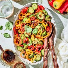 a bowl filled with sliced vegetables next to other bowls and spoons on a table