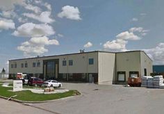 an industrial building with cars parked in the lot