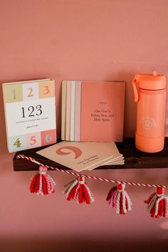 a shelf that has some books and other items on it with a pink wall in the background