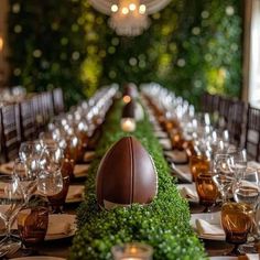 the table is set with an artificial football and greenery centerpiece, along with wine glasses