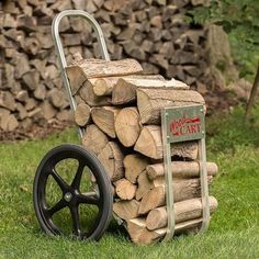 a wagon filled with firewood sitting on top of a green grass covered field next to a pile of logs