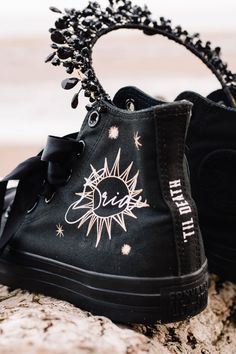 a pair of black shoes with sun and stars painted on them sitting on a rock