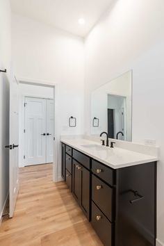 a large bathroom with two sinks and a mirror on the wall, along with wooden flooring