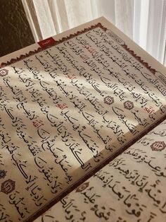 an old arabic calligraphy on display in a museum setting with white curtains behind it