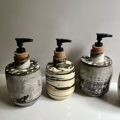 three soap dispensers sitting next to each other on a white counter top