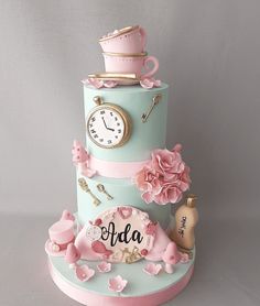 a three tiered cake decorated with pink flowers and an old clock on top is shown