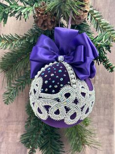 an ornament hanging from a christmas tree decorated with purple ribbon and beading