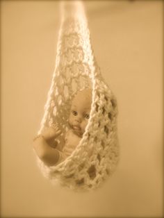 a baby in a crocheted hanging basket