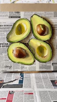 an avocado cut in half sitting on top of a newspaper