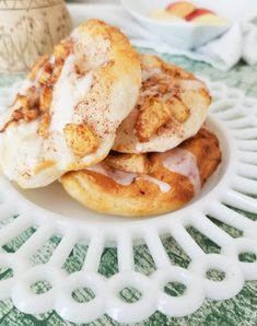 two cinnamon rolls on a white plate with sugar sprinkled on top, sitting on a green and white tablecloth