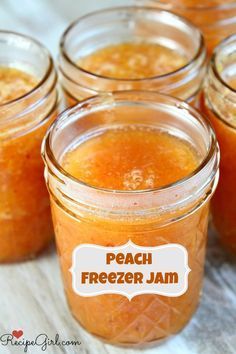 jars filled with peach freezer jam sitting on top of a table