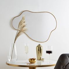 a table with some wine glasses and a vase on it, next to a mirror