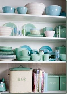 the shelves are filled with dishes and plates in pastel blue, green and white