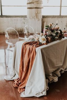 the table is set with white and brown linens, candles, and flowers on it