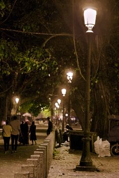 people are walking down the sidewalk at night