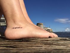 a close up of a person's foot with a boat in the background