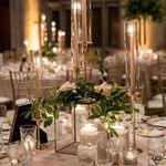 the centerpieces are surrounded by candles, flowers and greenery in glass vases