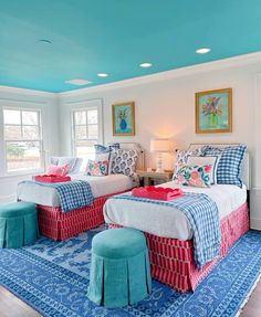 two beds in a room with blue and red decor on the walls, along with matching rugs