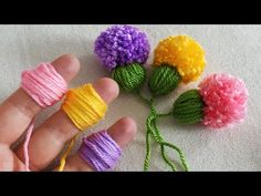 four different colored yarns are being held by someone's hand