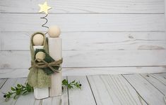 two wooden dolls sitting next to each other on top of a white wood floor with a star above them