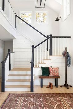 a wooden bench sitting under a stair case next to a set of white banisters