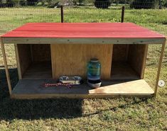 a wooden structure sitting in the middle of a field with a vase on top of it