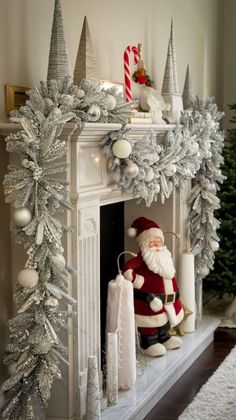 a mantel decorated for christmas with silver and white decorations on it, including a santa clause