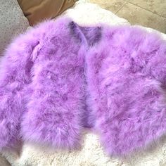 a purple furry coat laying on top of a bed