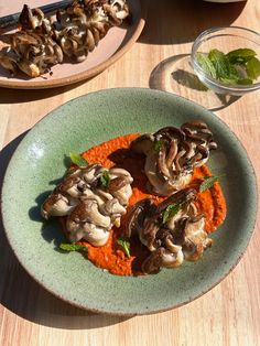 a green plate topped with food on top of a wooden table next to other plates