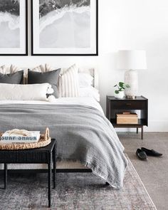 a bedroom with two framed pictures above the bed and an end table in front of it