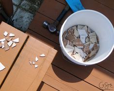 a bucket full of broken tiles sitting on top of a wooden table