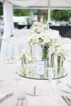 there are many vases with flowers in them on the table at this wedding reception