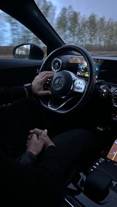 a person sitting in the driver's seat of a car with their hands on the steering wheel