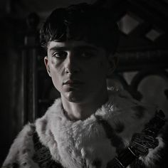 a young man in a fur coat stares into the camera