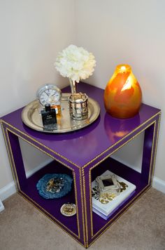 a purple and gold side table with flowers on it