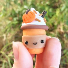 a hand holding a tiny toy with an ice cream cone on top