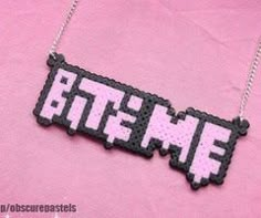 a necklace with the word mine written in white and black letters on pink fabric background