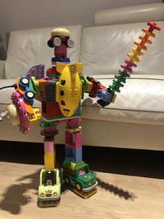 a toy robot that is sitting on the floor next to a couch with toys in it