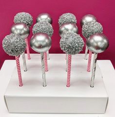 there are silver and pink lollipops on the white stand with candy sticks