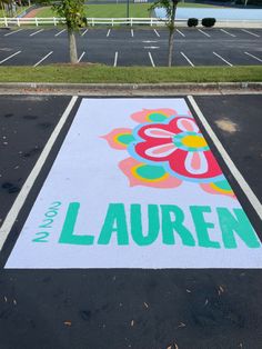 an empty parking lot with the name lauren painted on it and trees in the background