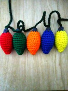 crocheted christmas lights are hanging on a string with black cord and green, yellow, red, orange, and blue beads