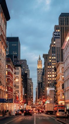 a city street filled with lots of tall buildings and cars driving down it at night