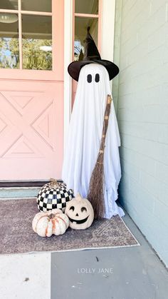 a halloween porch decoration with a broom, pumpkins and a ghost on the front door